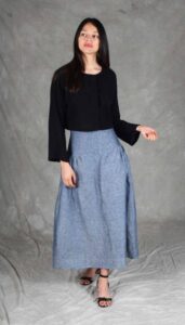 Modelo luciendo una falda confeccionada con el Patrón de Falda Fruncida para Principiantes "Noa", en tela de chambray azul. La prenda destaca por su canesú ancho, frunces sutiles y silueta evasé, ideal para costureras principiantes.