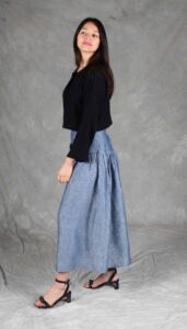 Modelo luciendo una falda confeccionada con el Patrón de Falda Fruncida para Principiantes "Noa", en tela de chambray azul. La prenda destaca por su canesú ancho, frunces sutiles y silueta evasé, ideal para costureras principiantes.