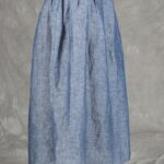 Model wearing a skirt sewn from the Noa gathered skirt sewing pattern, made in blue chambray fabric, featuring a wide yoke waistband and soft gathers, perfect for confident beginners and everyday wear.