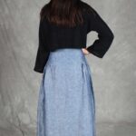 Model wearing a skirt sewn from the Noa gathered skirt sewing pattern, made in blue chambray fabric, featuring a wide yoke waistband and soft gathers, perfect for confident beginners and everyday wear.
