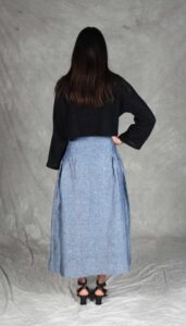 Modelo luciendo una falda confeccionada con el Patrón de Falda Fruncida para Principiantes "Noa", en tela de chambray azul. La prenda destaca por su canesú ancho, frunces sutiles y silueta evasé, ideal para costureras principiantes.