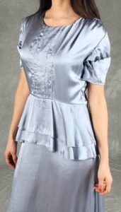 Woman wearing a glamorous silver satin dress with vintage details and peplum waist, perfect for special occasions, created with an event dress sewing pattern