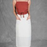 CHARLIZE skirt sewing pattern with large patch pockets: front view of the white midi skirt with hands in the pockets.