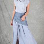Patrón de costura de falda larga MILLISIERES: falda azul claro fruncida en movimiento, con abertura delantera bajo el canesú gris oblicuo.