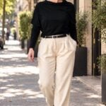 Patron de couture pantalon à plis AUDREY : femme marchant dans une rue arborée en pantalon crème à plis et haut noir