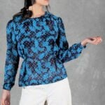 AGATHE blouse sewing pattern: front view of the navy-and-blue patterned blouse with gathered waist and long sleeves, paired with light trousers.