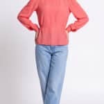 AGATHE blouse sewing pattern: front view of a coral-pink long-sleeved blouse with a gently shaped waist, worn with blue jeans.