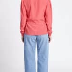 AGATHE blouse sewing pattern: back view of the coral-pink long-sleeved blouse, styled with blue jeans.