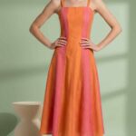 Model wearing the yellow DOMITIA sleeveless panel dress sewing pattern, with fine shoulder straps, a clean neckline and a fitted bodice opening into a flared skirt.