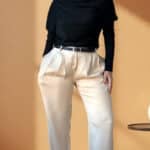 Patron de couture pantalon à plis AUDREY : satin crème à plis, top drapé noir et ceinture, main sur la hanche, fond orangé