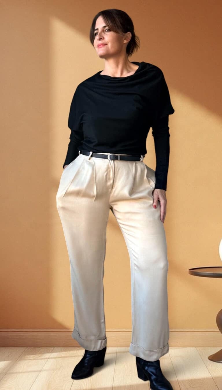 Patron de couture pantalon à plis AUDREY : satin crème à plis, top drapé noir et ceinture, main sur la hanche, fond orangé