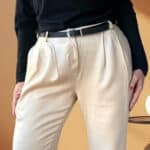 Patron de couture pantalon à plis AUDREY : gros plan sur le devant plissé et la taille ceinturée, mains sur les hanches