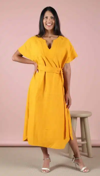 Woman wearing a handmade yellow midi dress created from a sewing pattern, with short sleeves and a waist tie