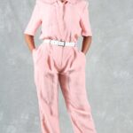EMMA pink jumpsuit sewing pattern with a white belt, straight trouser legs and neatly turned-up hems.