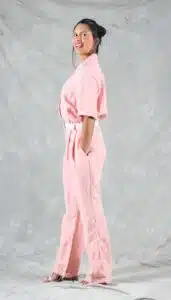 Side view of a woman wearing a DIY pink linen jumpsuit with short sleeves, pleated pants, and in-seam pockets – made from a stylish summer jumpsuit sewing pattern.