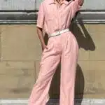 EMMA jumpsuit sewing pattern: woman in a pale-pink collared jumpsuit with short sleeves, white belt and straight trousers.