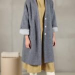 CHAMADE oversized coat sewing pattern presentation for a grey, longline V-neck coat with wide sleeves and turned-up cuffs, paired with a neutral outfit.
