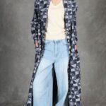 Vorderansicht des Schnittmusters für den ausgestellten langen Mantel PERSEPHONE, geometrisch gemustert über hellblauer weiter Jeans.