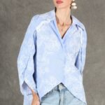 GALATEE collared shirt sewing pattern: loose pale-blue floral shirt with a curved hem and long sleeves, worn untucked with jeans.