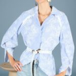 GALATEE collared shirt sewing pattern: model in a pale-blue white-floral blouse cinched with a white belt over light-wash jeans.