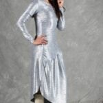 HYPE dress sewing pattern: silver long-sleeved dress with gathered waist, model posing with a hand on her hip