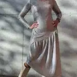 HYPE dress sewing pattern: front view of a silver long-sleeved dress with gathered waist and draped asymmetric skirt.