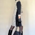 Patrón de vestido LISA con cuello bebé en una foto lateral, combinado con botas altas negras, gafas de sol y bolso negro grande.