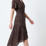 SIENNA wrap dress sewing pattern: side view of a model walking in the polka-dot dress, showing the moving asymmetric skirt.