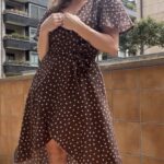 SIENNA wrap dress pattern for women: outdoor three-quarter view of the brown dotted dress with crossed neckline and flowing skirt.