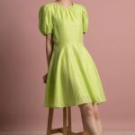 Schnittmuster Puffärmelkleid DOLCE: limettengrünes Kleid mit gerafftem Halsausschnitt und ausgestelltem Rock, sitzende Ansicht.