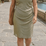 NAIA draped sleeveless dress sewing pattern in pale sage-green fabric, shown from the front in an outdoor setting.