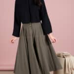 LOUISE circle skirt sewing pattern: khaki flared midi skirt styled with a black top against a pink studio background.